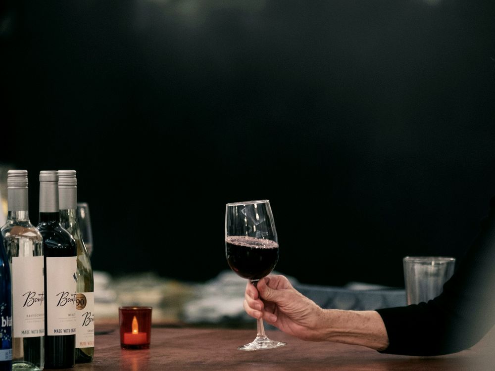 Einzelne Person mit einem Glas Rotwein an einem dunklen Tresen
