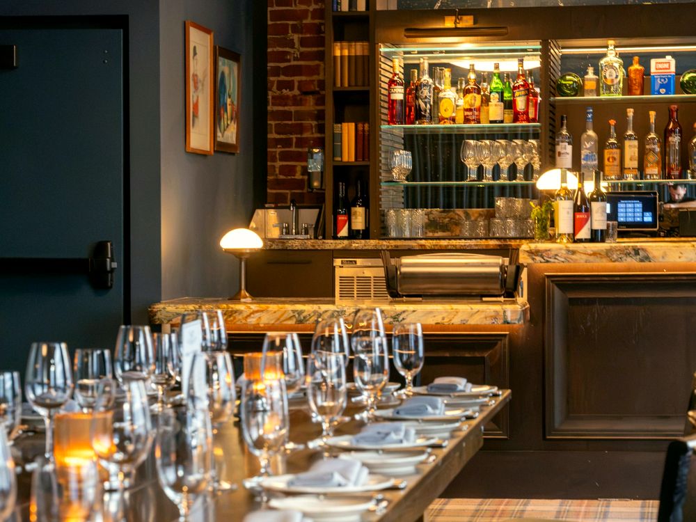 Lange eingedeckte Tafel in einem Restaurant mit Bar im Hintergrund