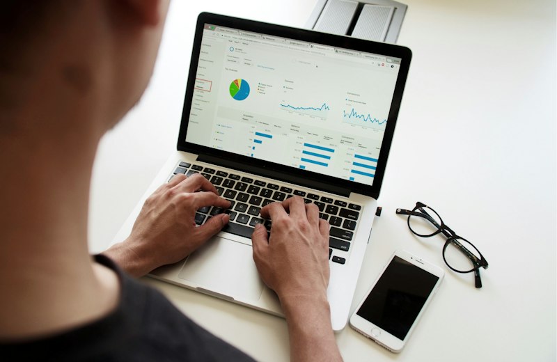 Hände tippen auf einem Laptop mit Diagrammen