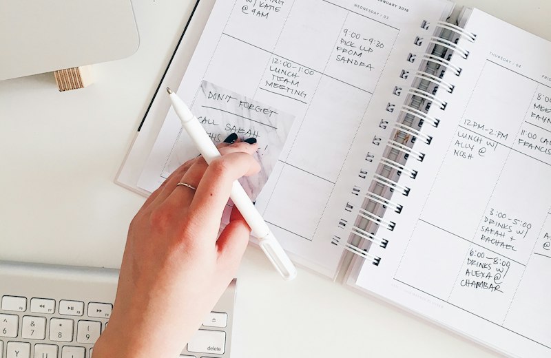 Hand schreibt Termine in einen Planer
