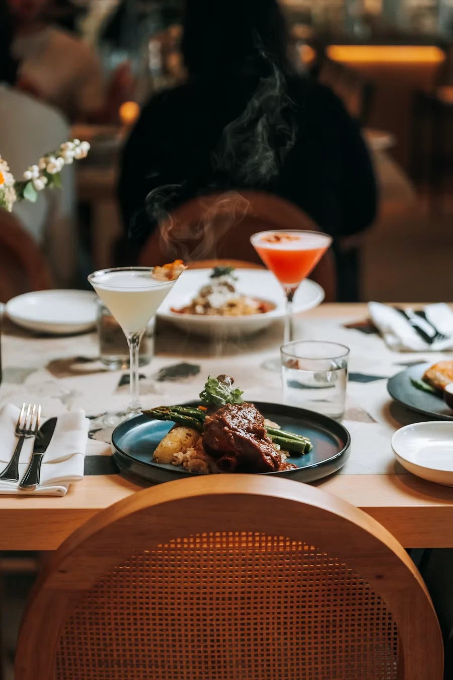 Servierter Tisch im Restaurant mit Hauptgang und Cocktails