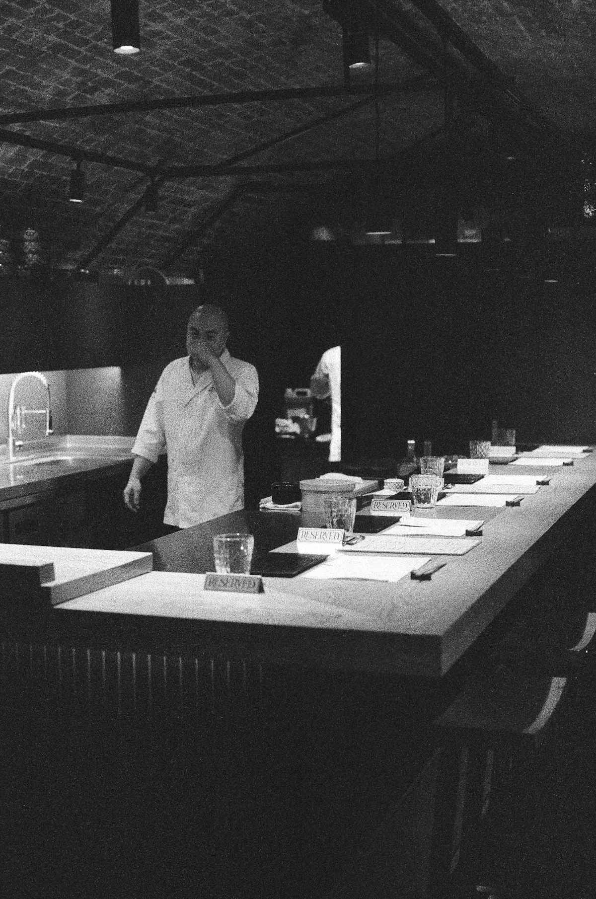 Koch steht abends allein in einem leeren Restaurant, Schwarzweißfoto